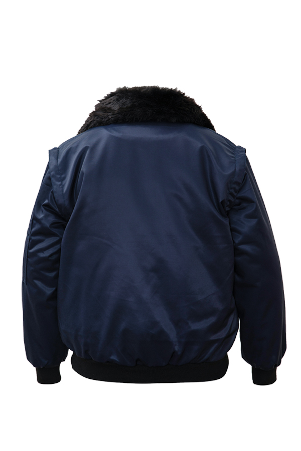 Ein Mann in einer signalgelb-schwarzen Korntex-Pilotenjacke steht vor einem Gebäude