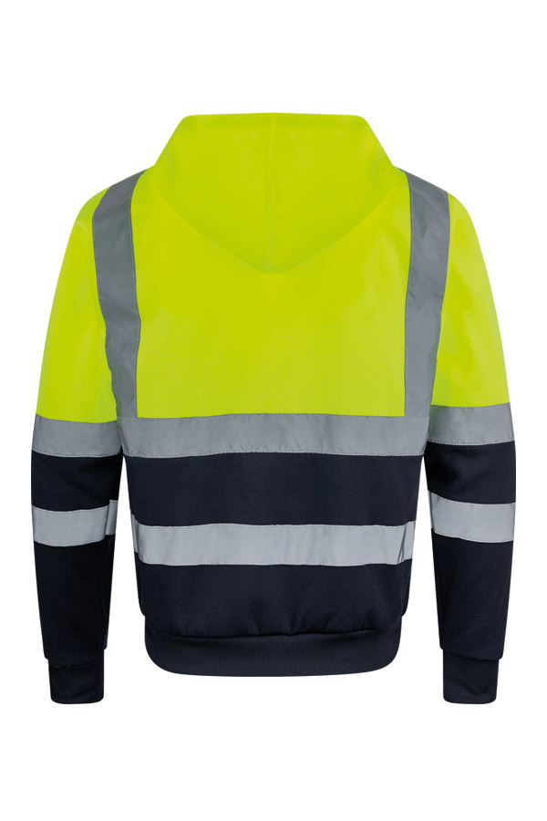 Erwachsener in signalgelbem Korntex-Hoodie mit Zipper und Reflexstreifen in einem industriellen Umfeld